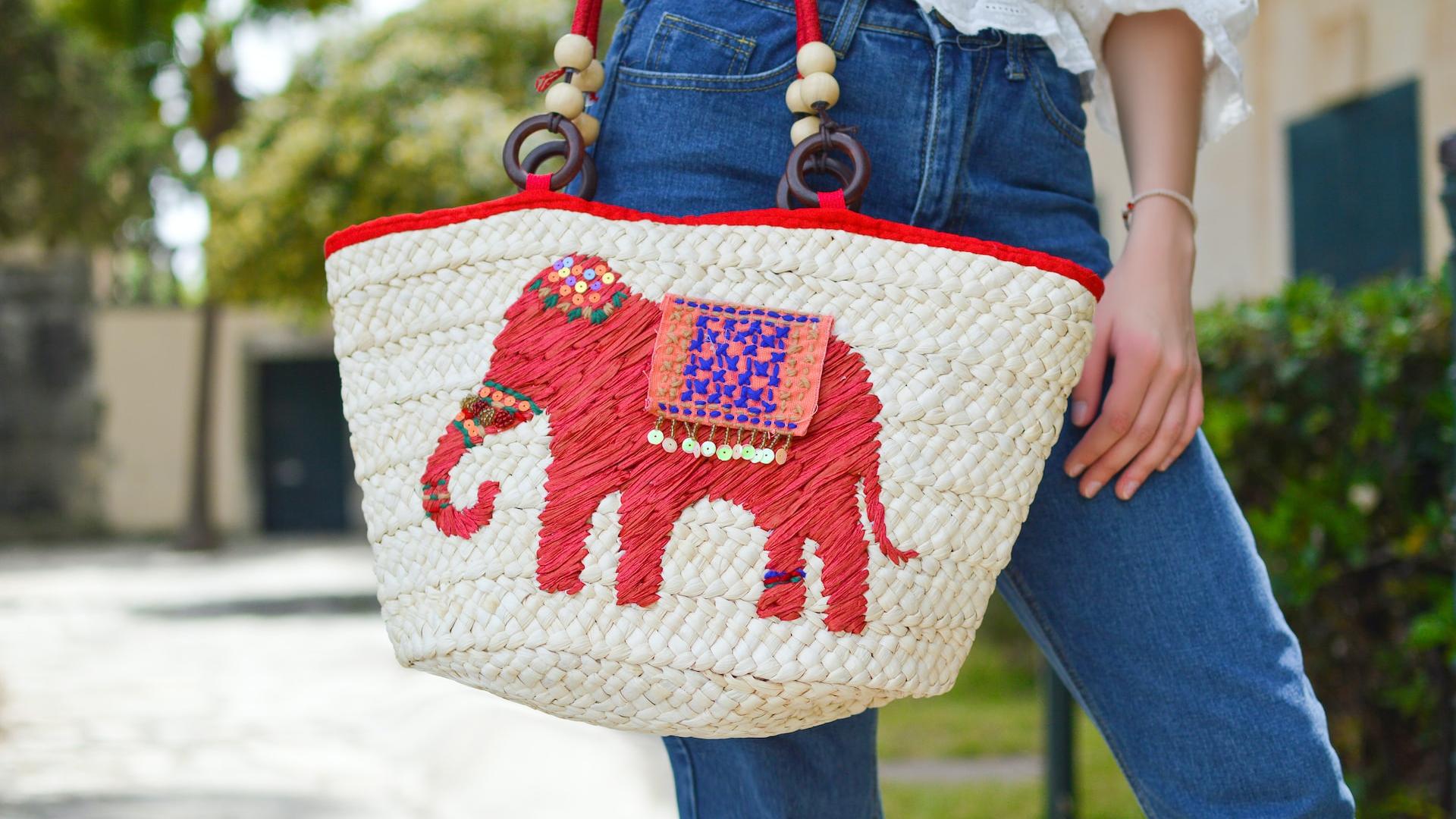 person holding white and red elephant graphic tote bag close-up photo